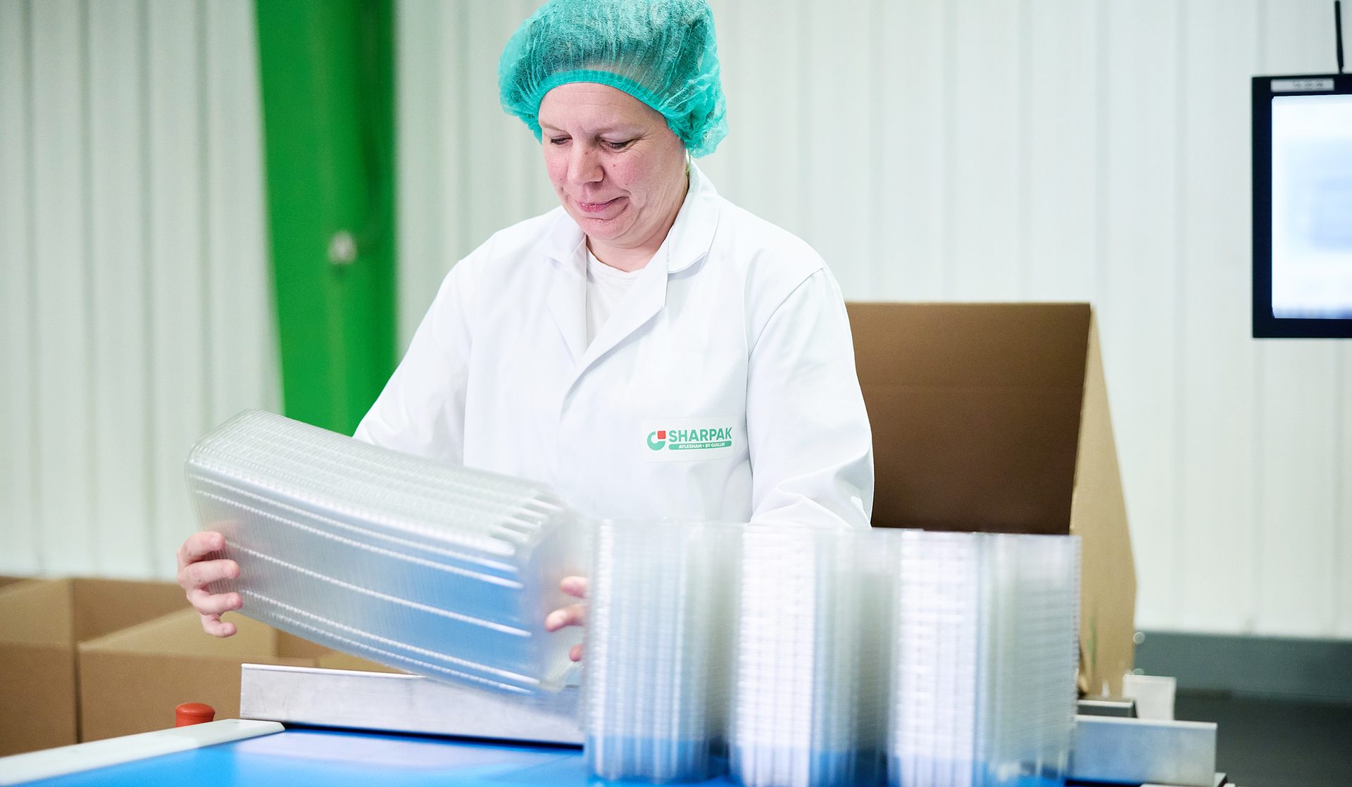 Image of SHARPAK employee working with clamshells for fresh produce packaging.