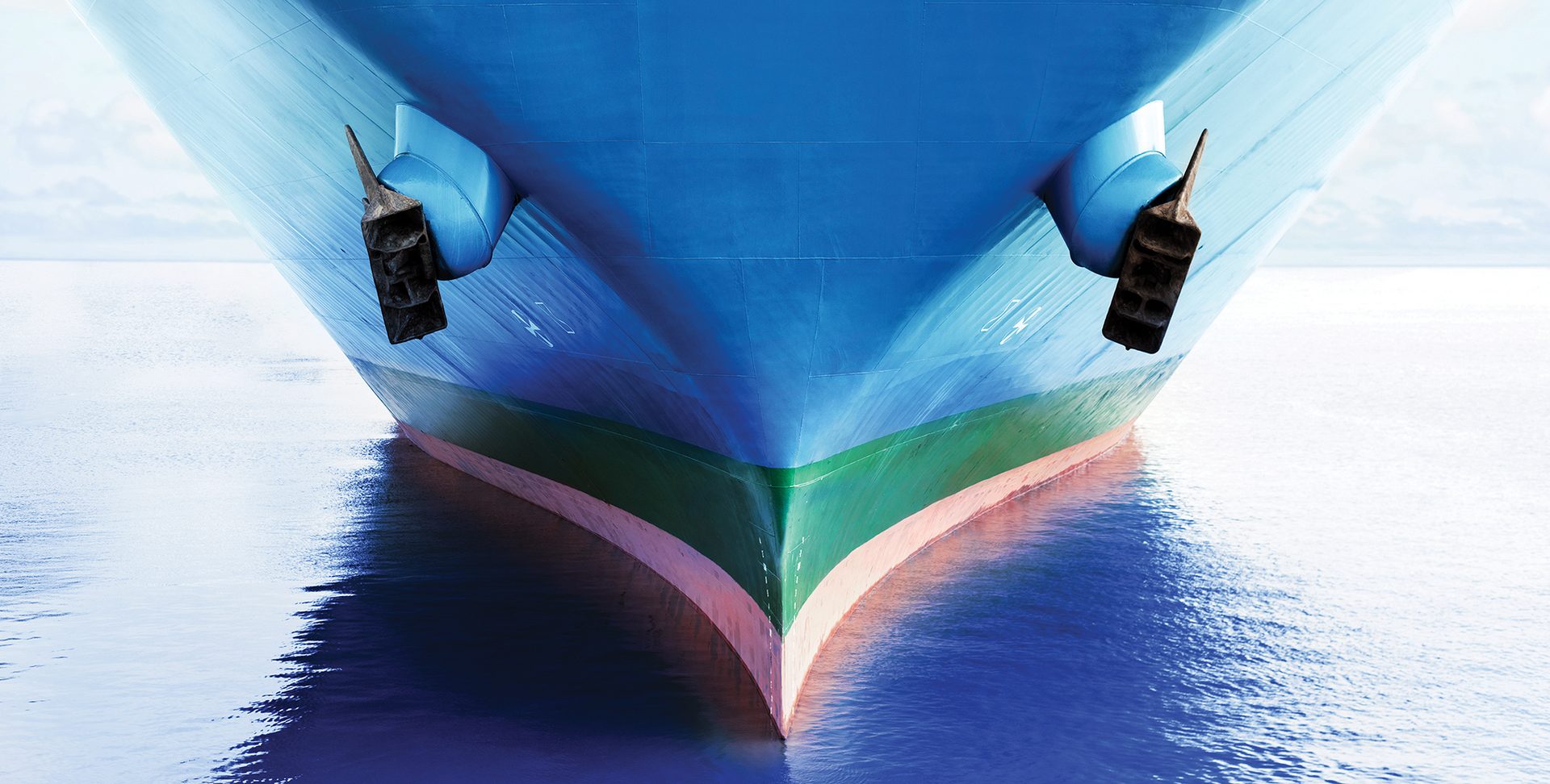 Front view of large blue merchant cargo ship with clean hull in the middle of the ocean