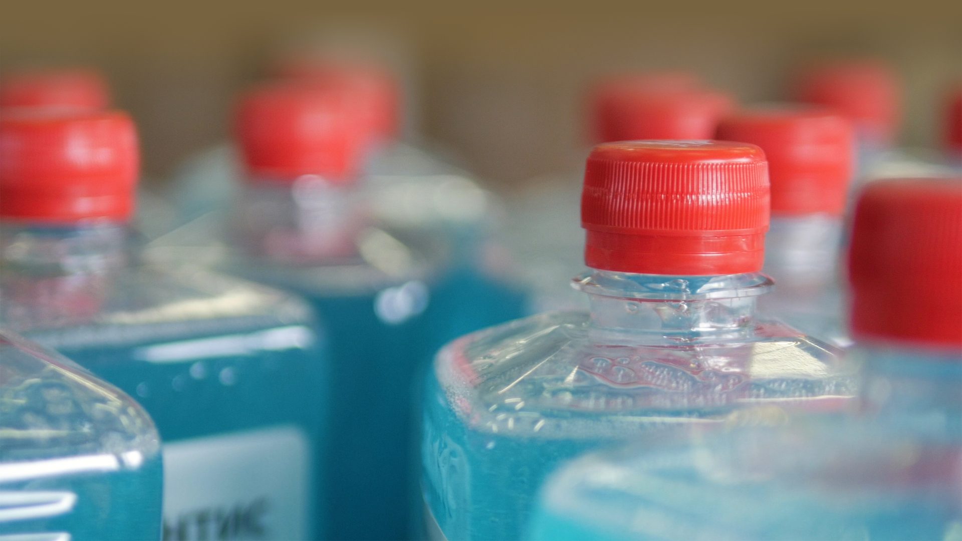 Conveyor with many bottles with blue liquid and red lids