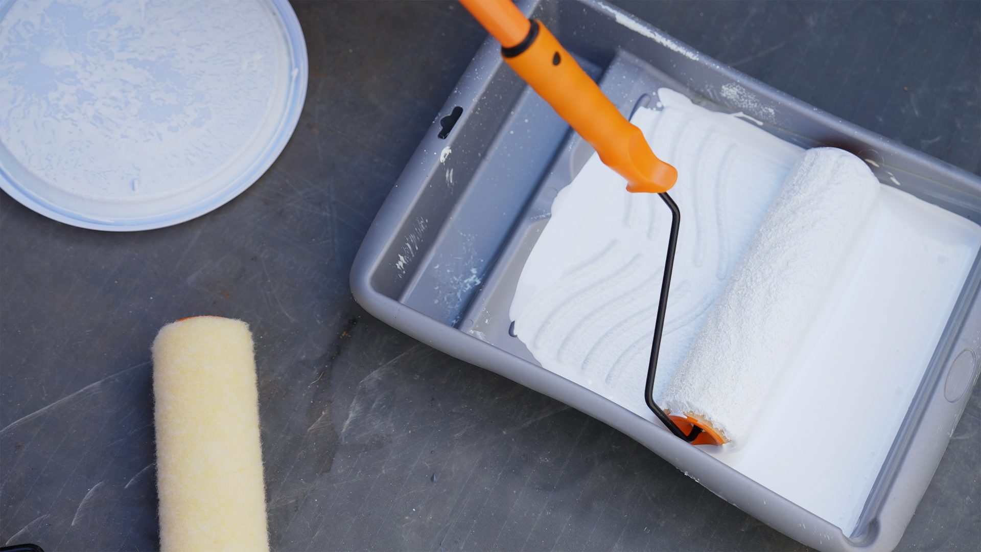 paint roller in tray with white paint