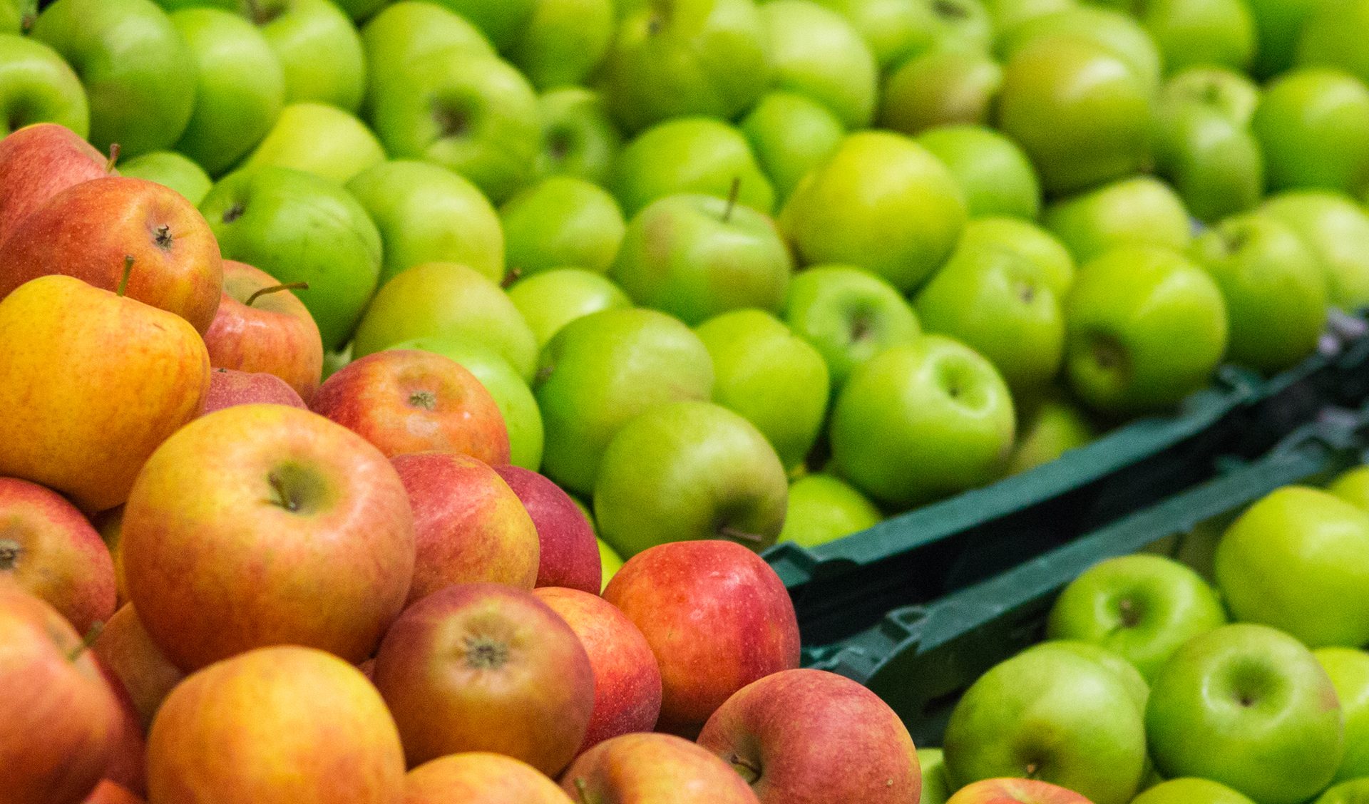 A market display of fresh red, yellow, and green apples.