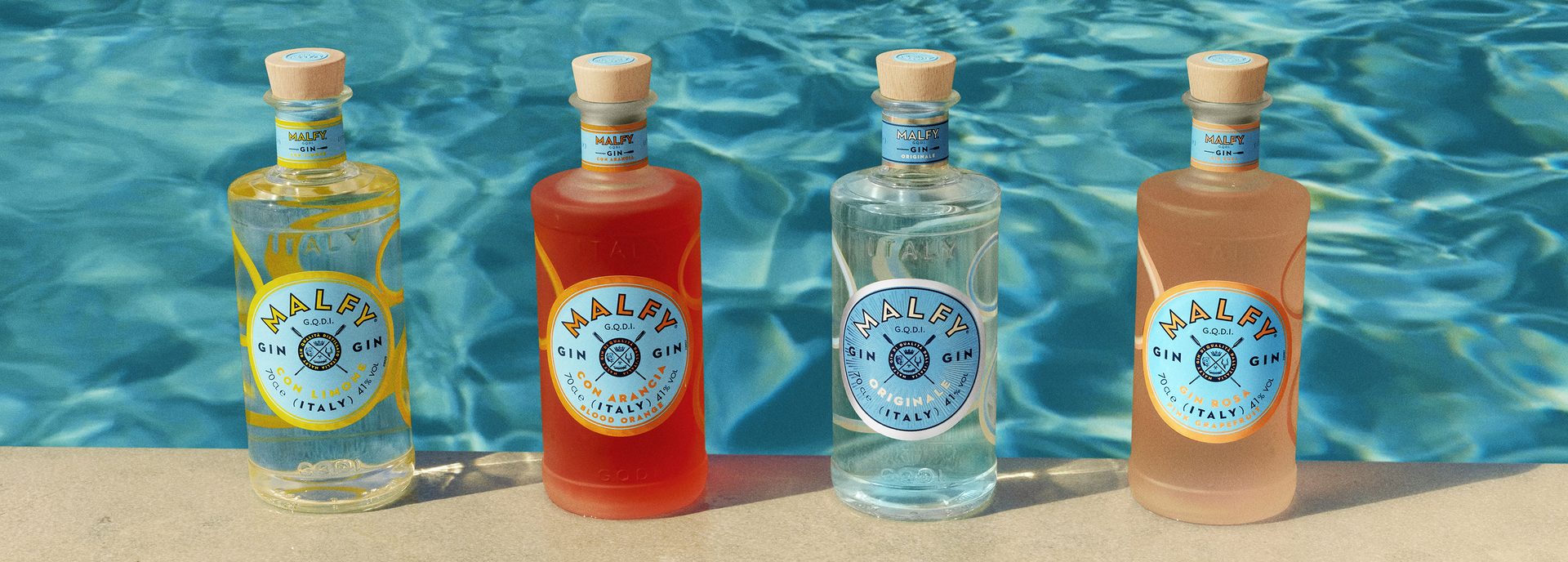 Various Malfy bottles featuring the new design lined up by pool