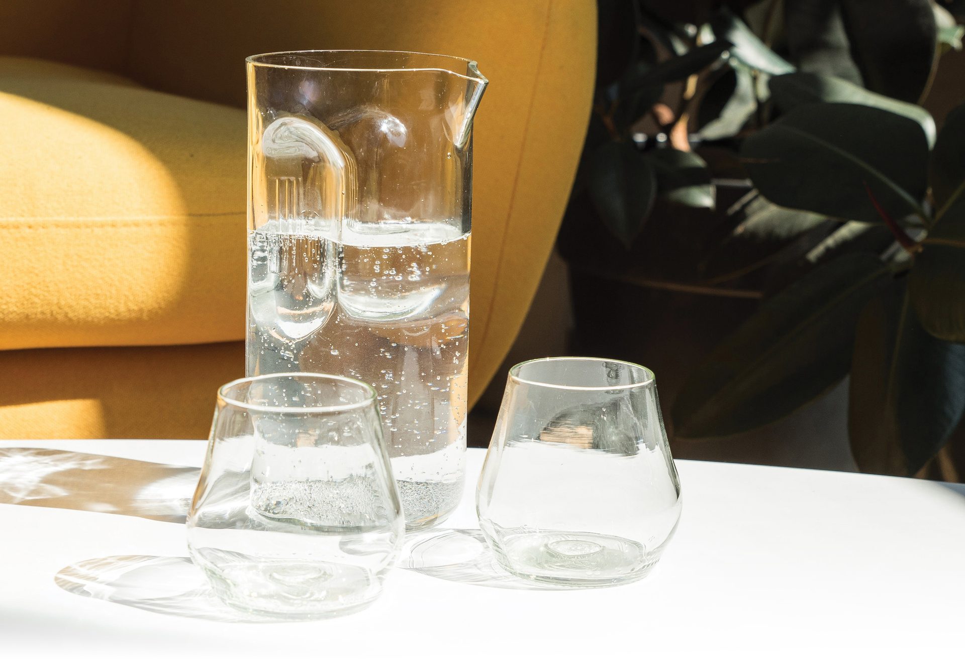 Glass container of water and drinking glasses on a table in a home