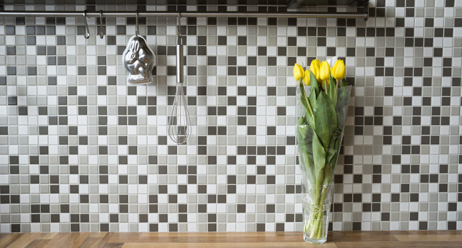 Black, white and gray peel and stick tile in a kitchen with yellow flowers in a vase