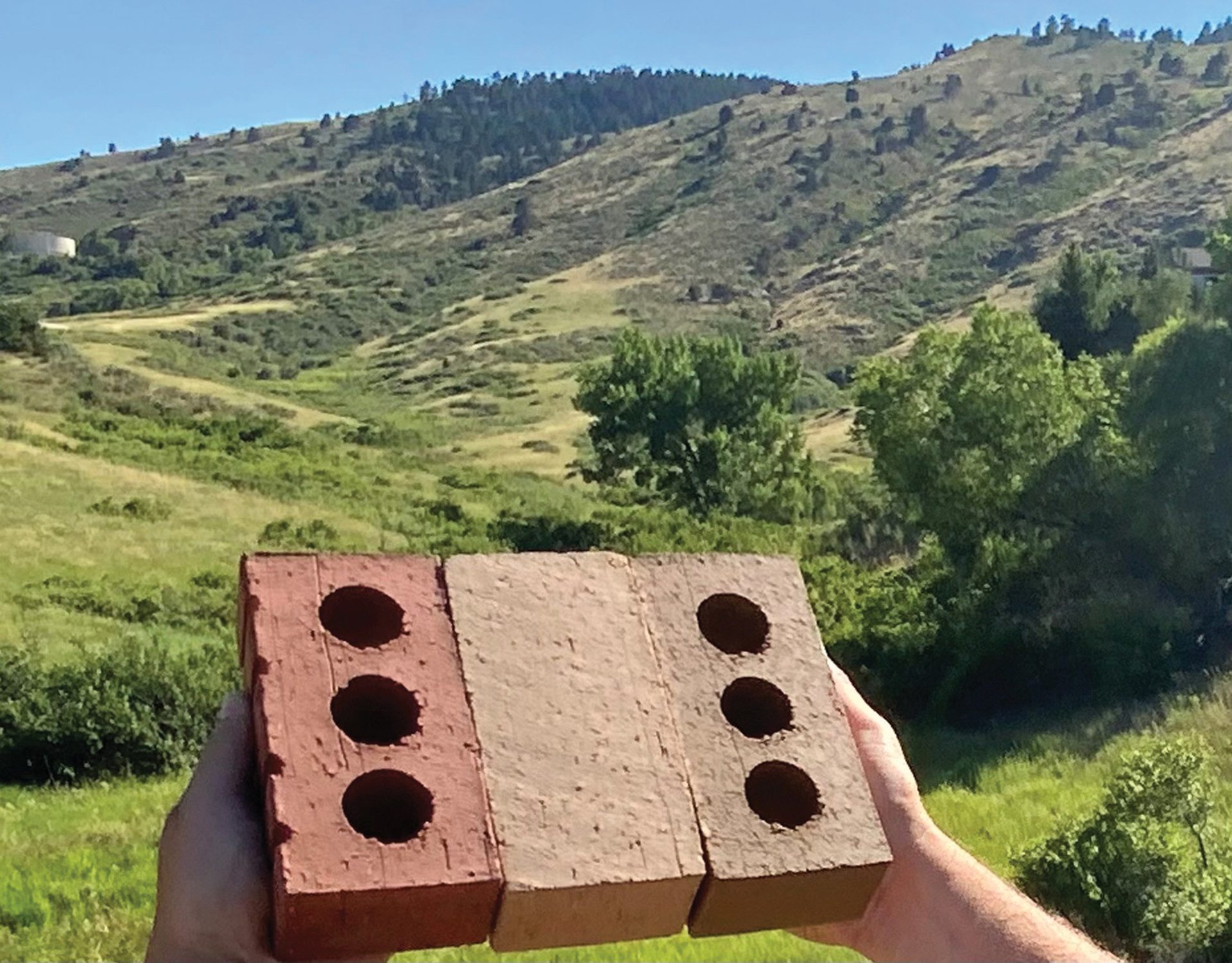 Clay bricks held up against a hilly landscape