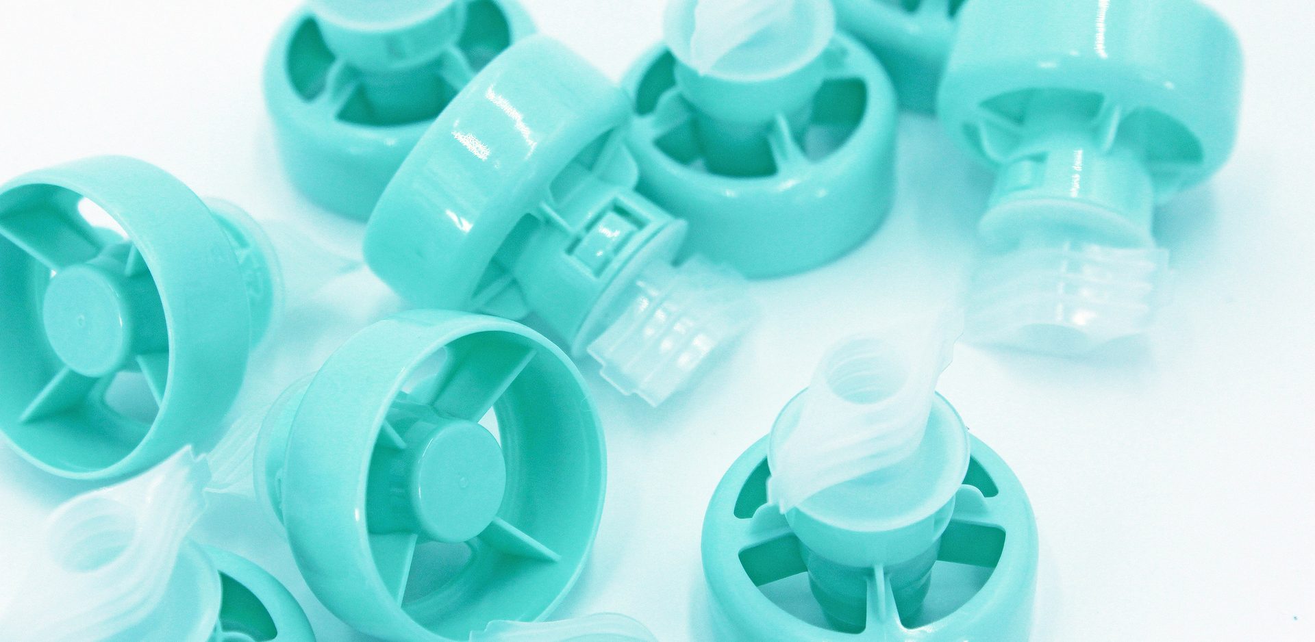 Scattered light blue plastic dispenser pump tops.Image of caps and spouts.