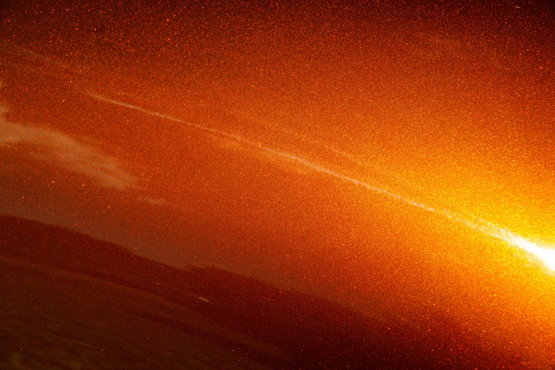 Macro of muscle car metallic paint job, orange tone with sparkles. 