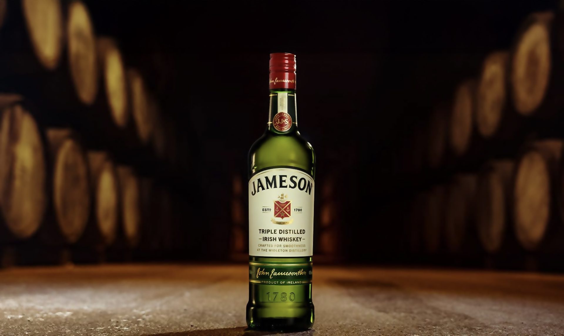 Jameson bottle standing upright with distillery in background 