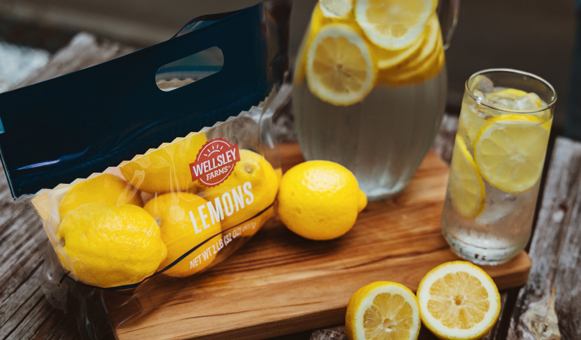 Image of lemons on a picnic table alongside flexible packaging for lemons and a pitcher of lemonade.