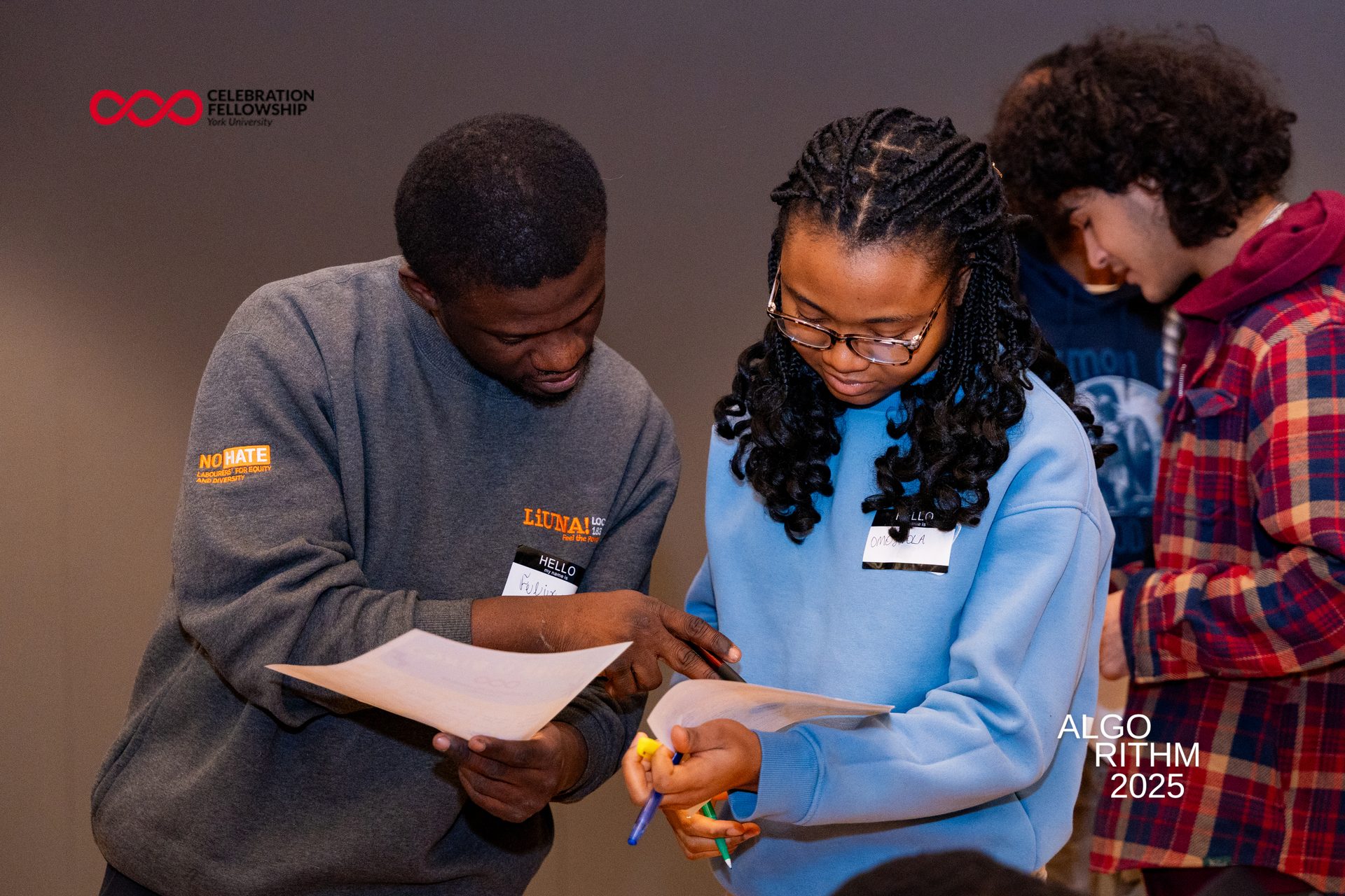 Two young people, Felix and Omoola, reviewing documents at a 'Celebration Fellowship' event.