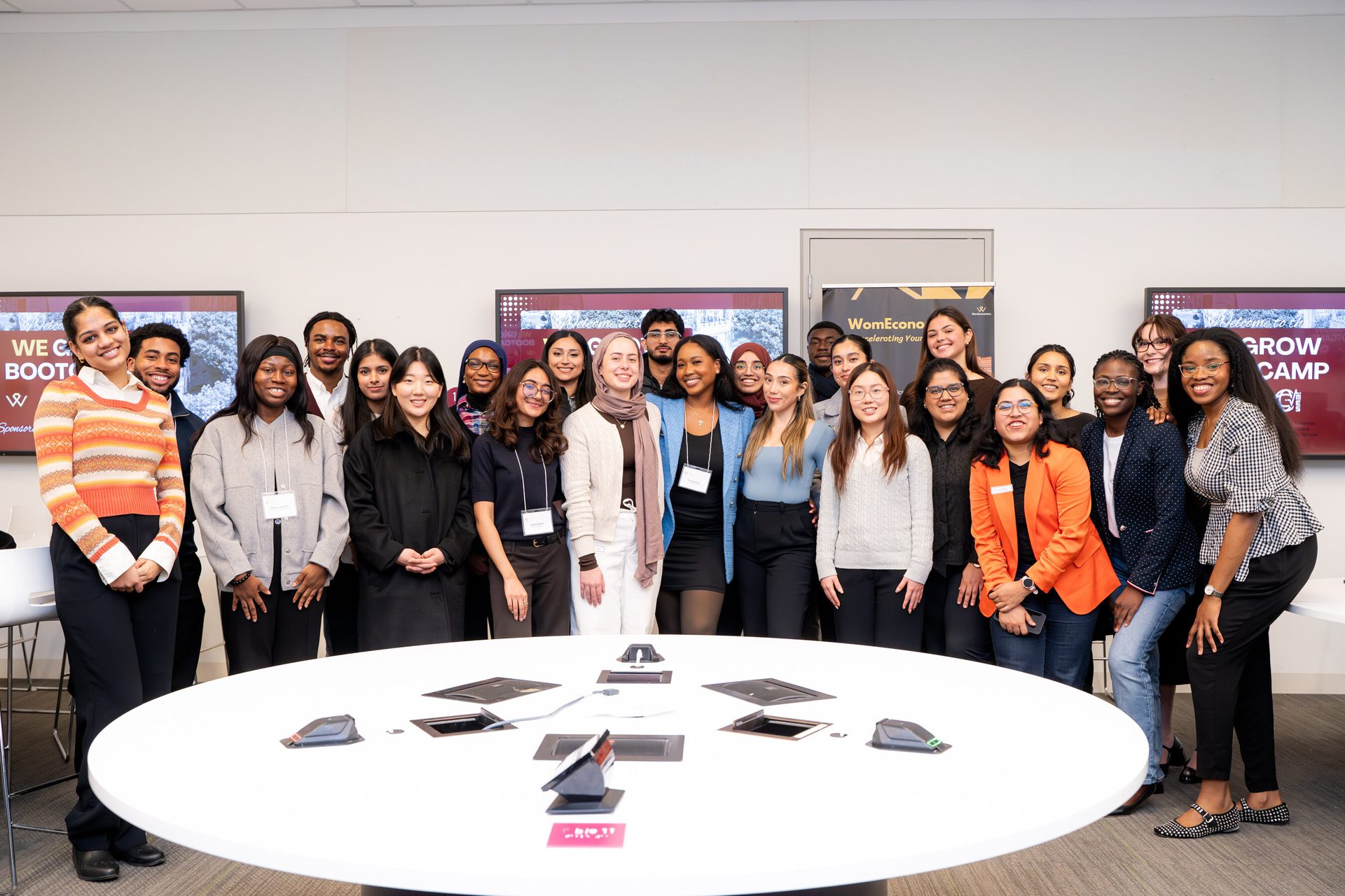 Diverse group of young people smiling around a table at a WomEcono event.