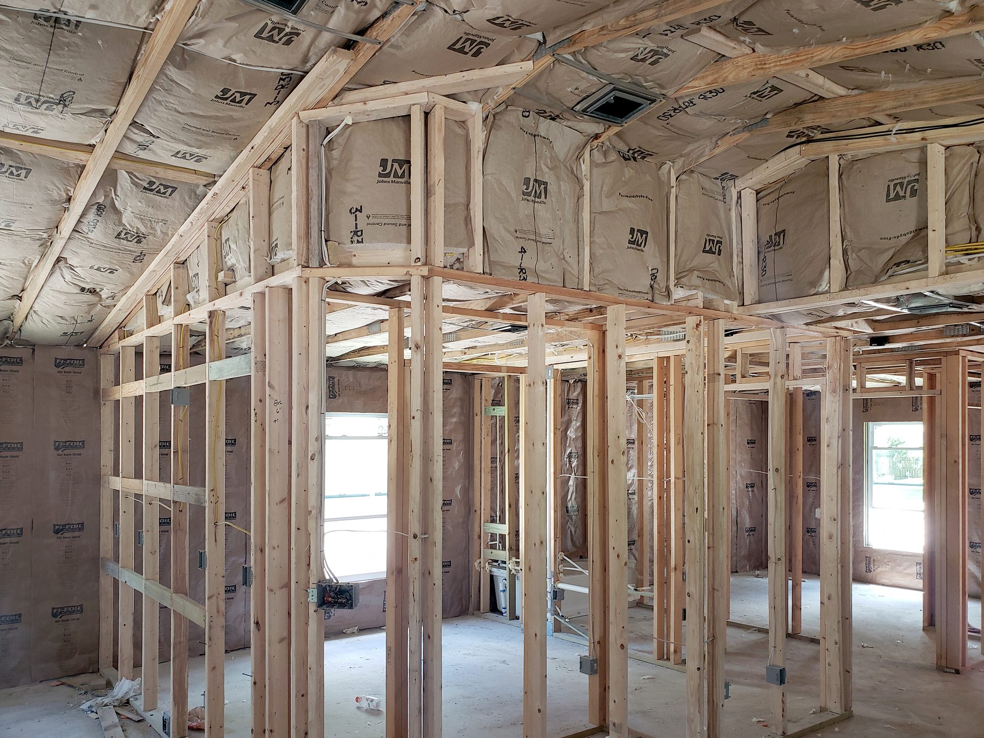 Interior view of a residential building under construction, showing exposed wooden framing and insulation.