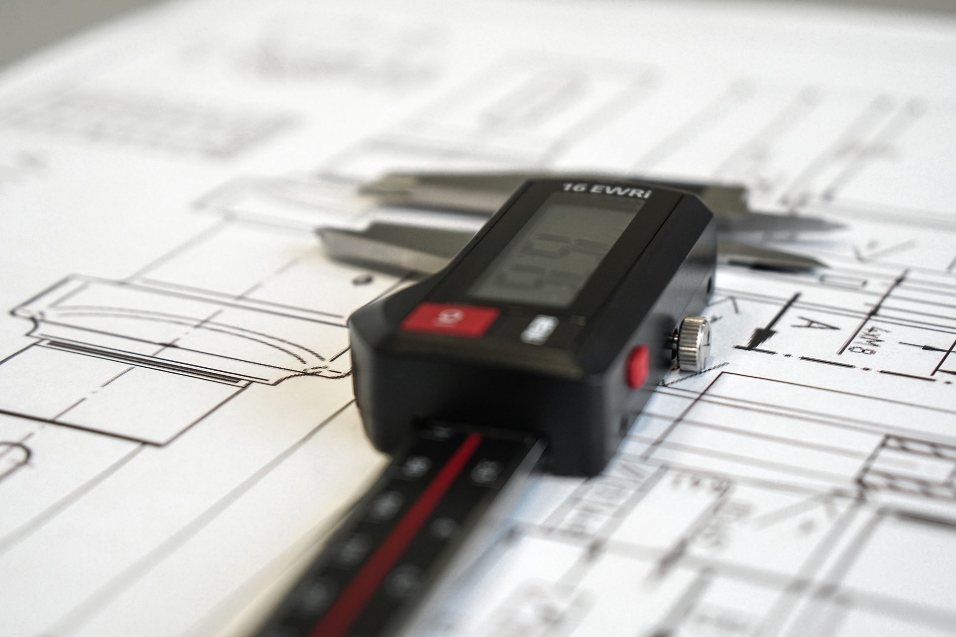 Digital depth gauge on engineering blueprints, showing measurements for precision work.