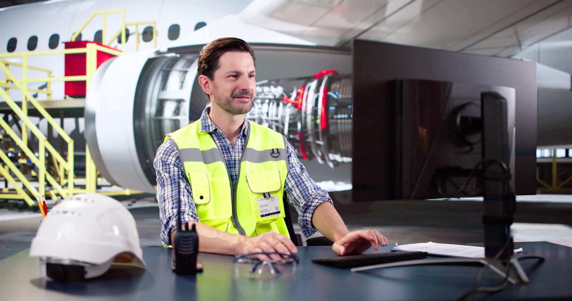 Worker at computer with jet behind him