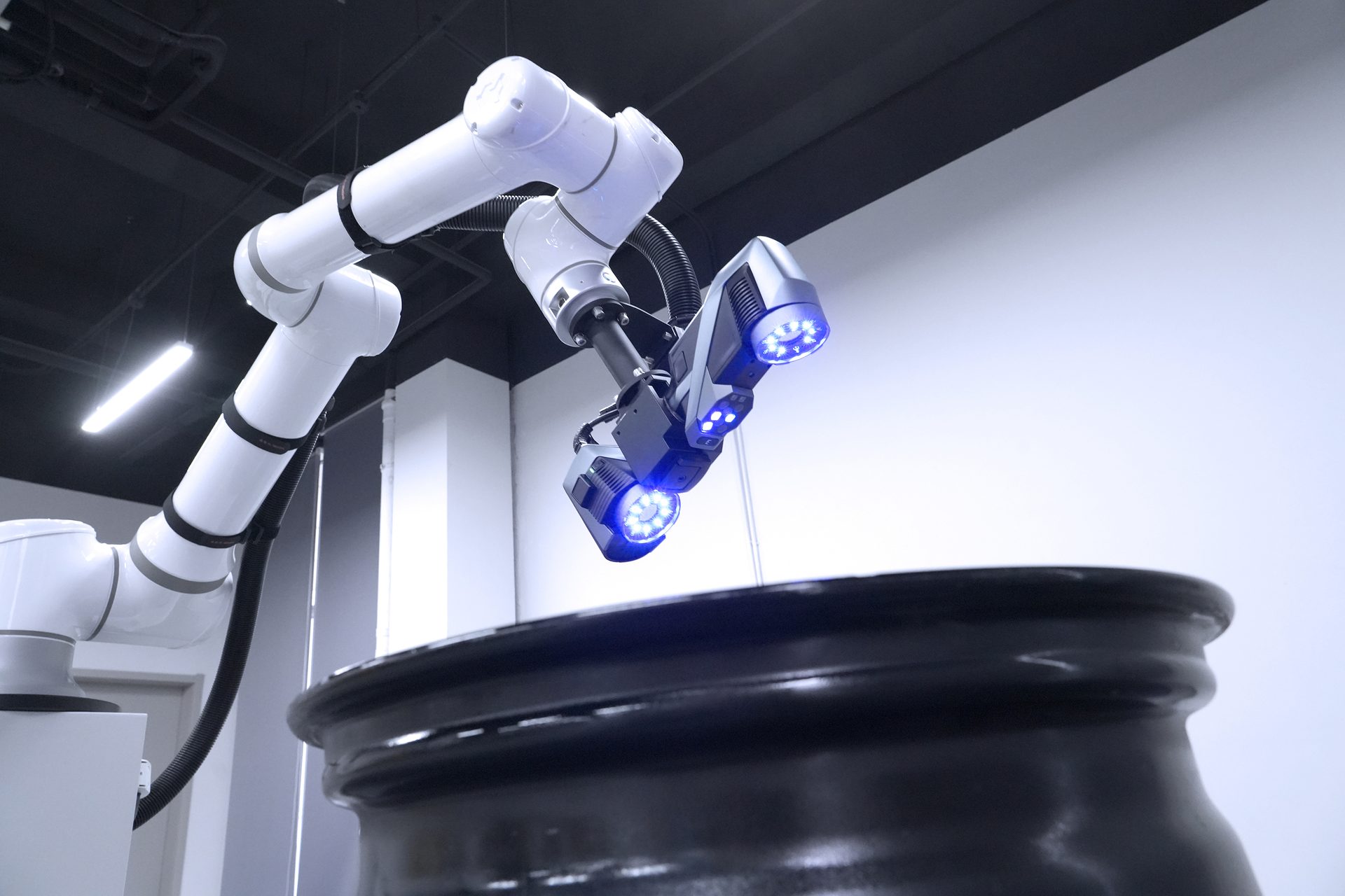 Robotic arm with blue-lit scanner inspecting a dark object.