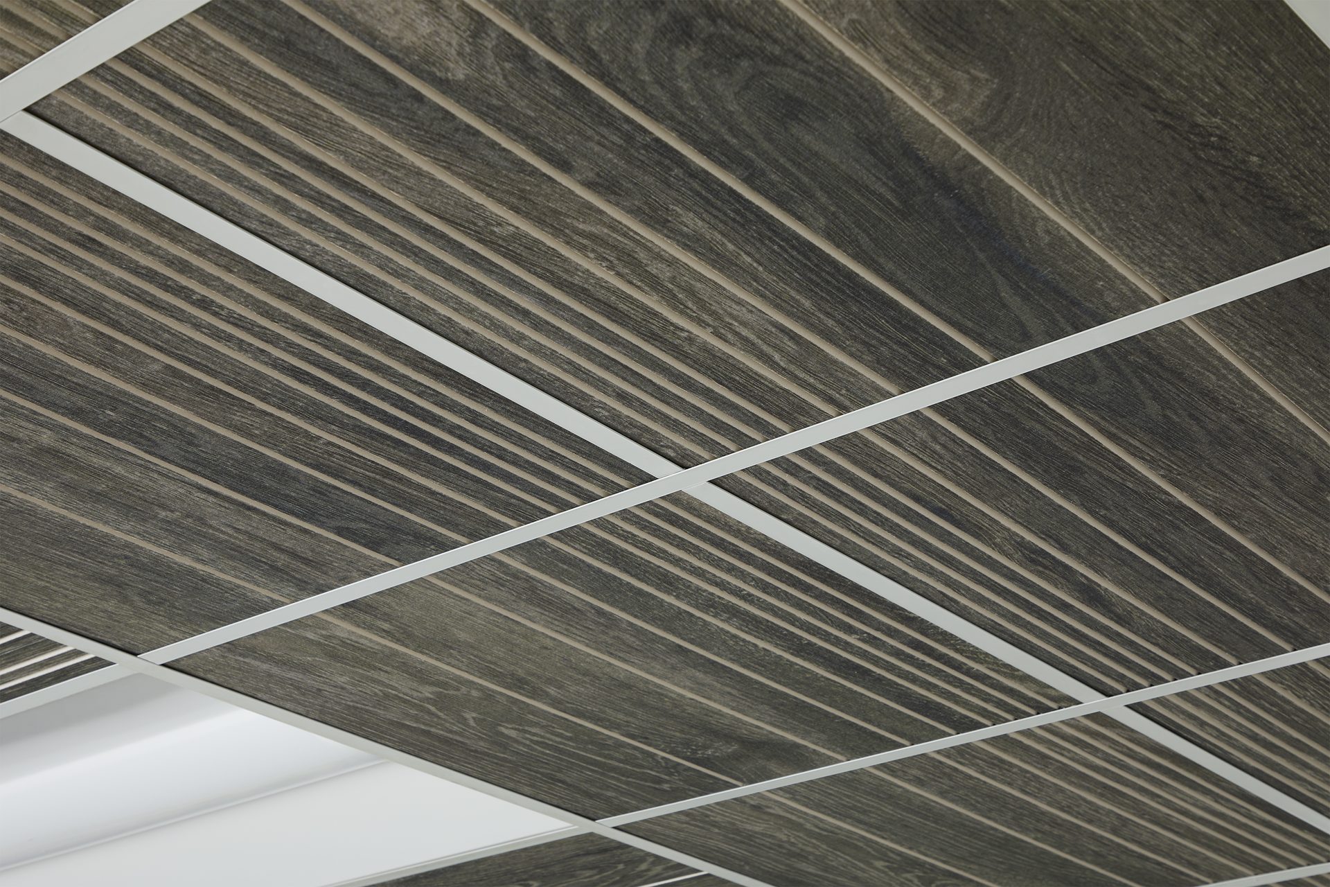 Dark wood-look linear ceiling panels within a white grid, with a light fixture.