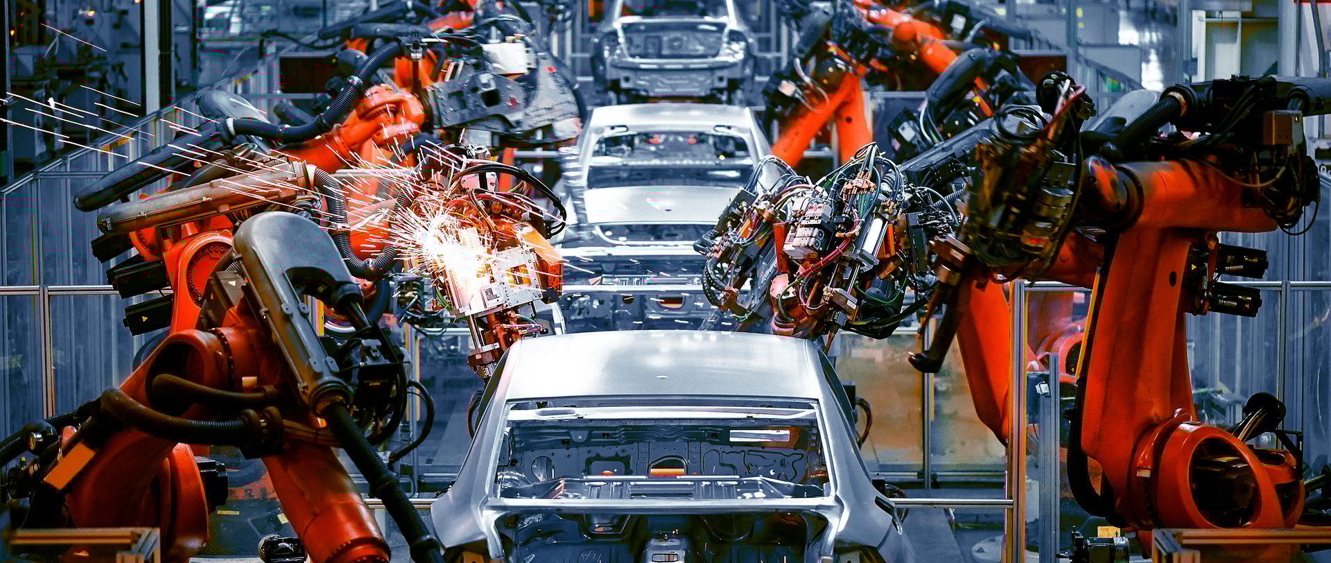Robotic arms welding car bodies on an assembly line, with bright sparks flying.