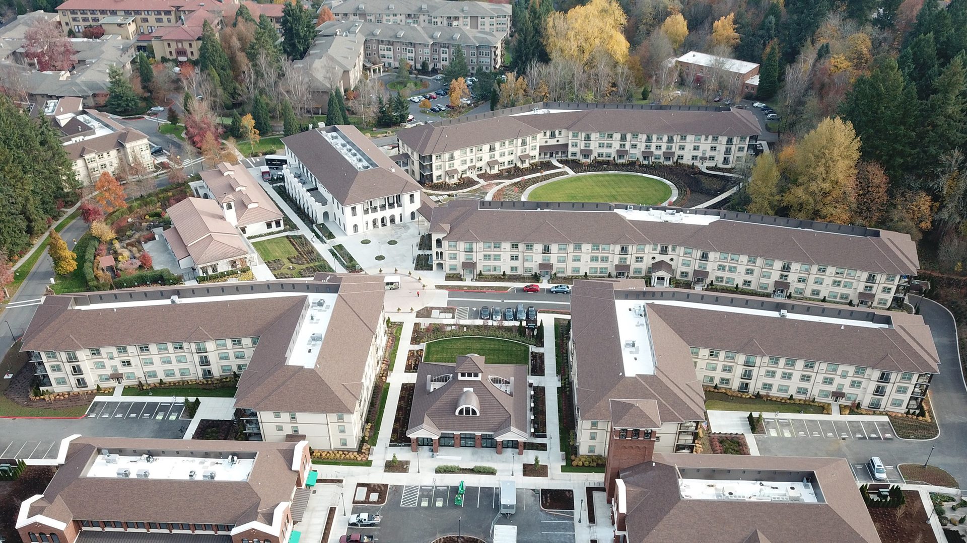 Aerial view of a sprawling residential complex with buildings, green lawns, and vibrant autumn trees.