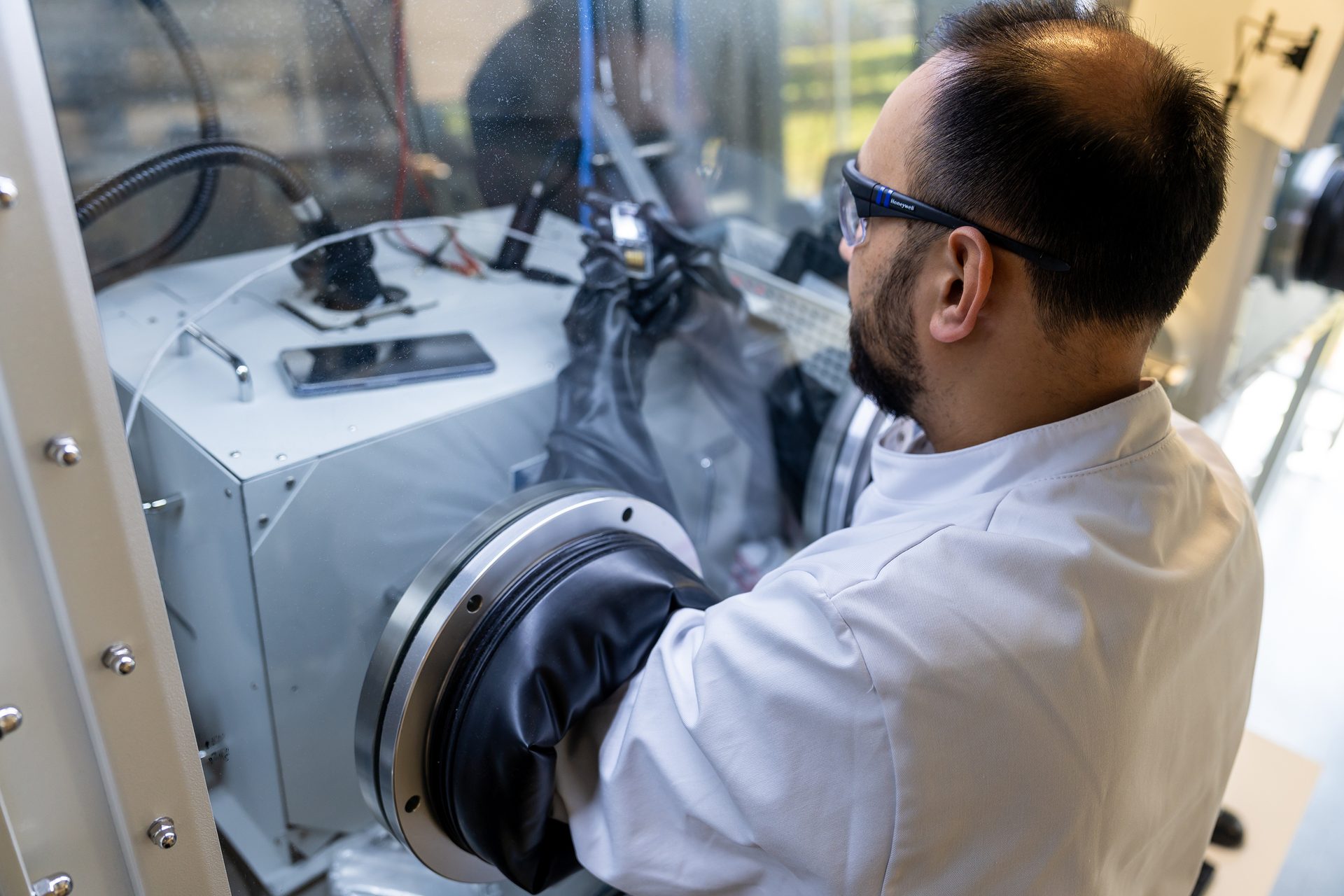A scientist preparing a quantum dot photodiode device for electrical measurement in a nitrogen filled glove box.