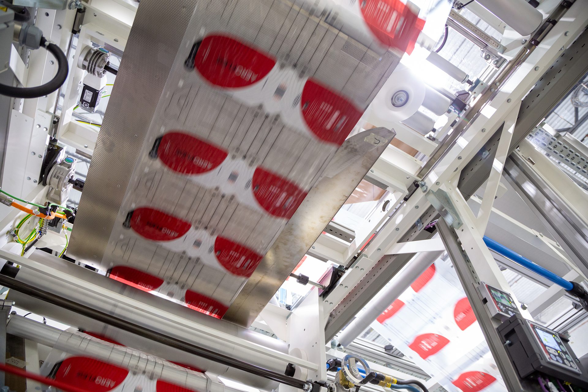 Packaging machine processing film with repeating red patterns and "AERO" text.
