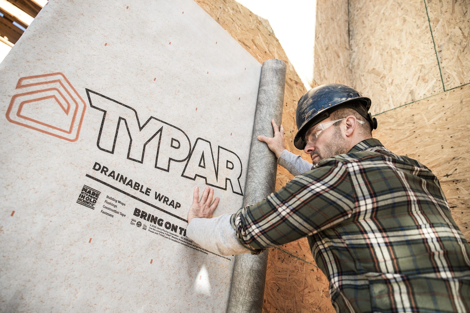 Man installing Typar drainable wrap on a building wall.