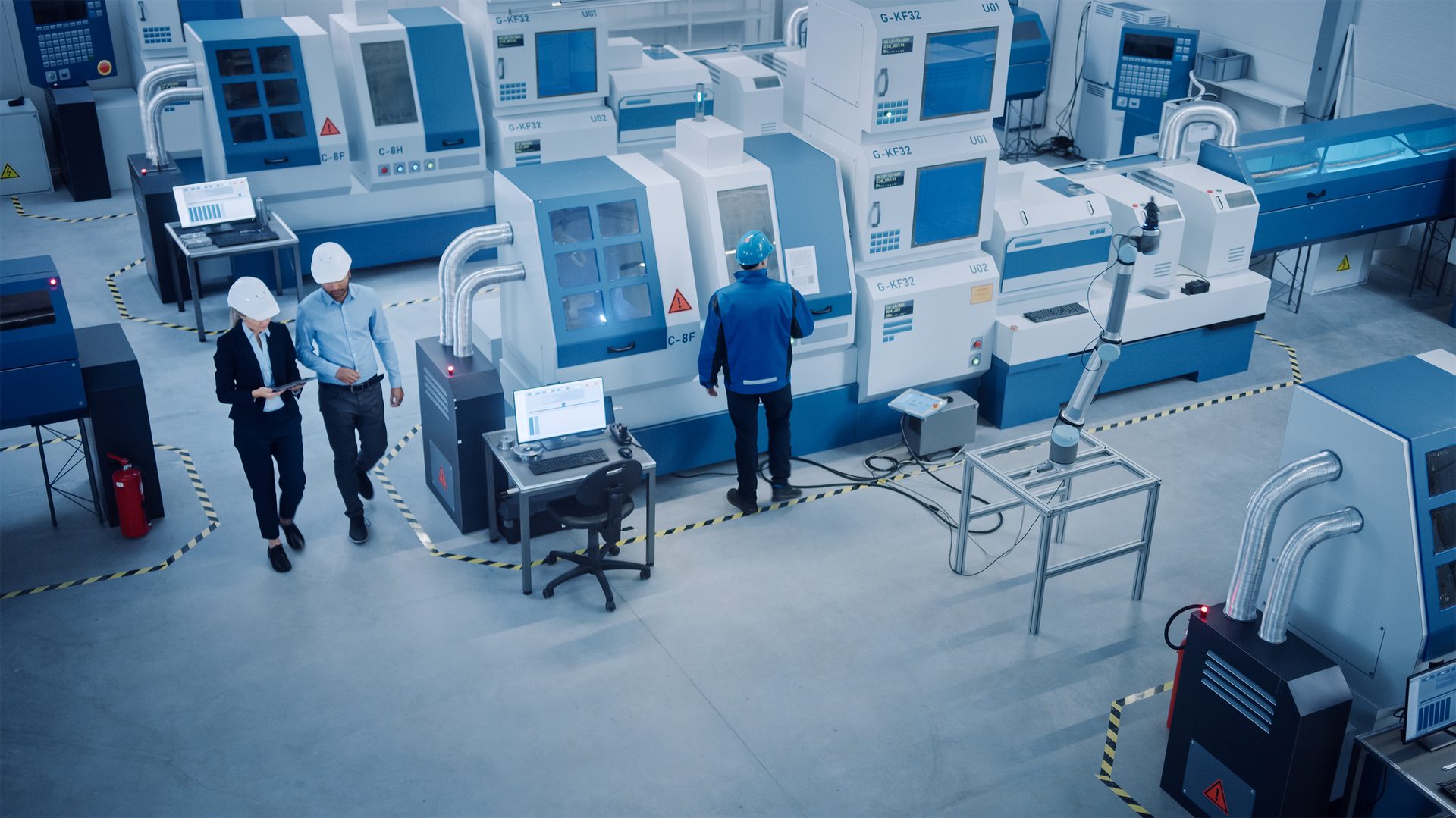 Modern factory with workers, robotic arm, and blue & white CNC machines.