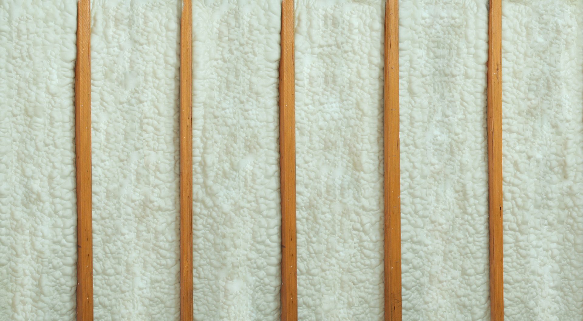 Spray foam insulation between wooden beams.