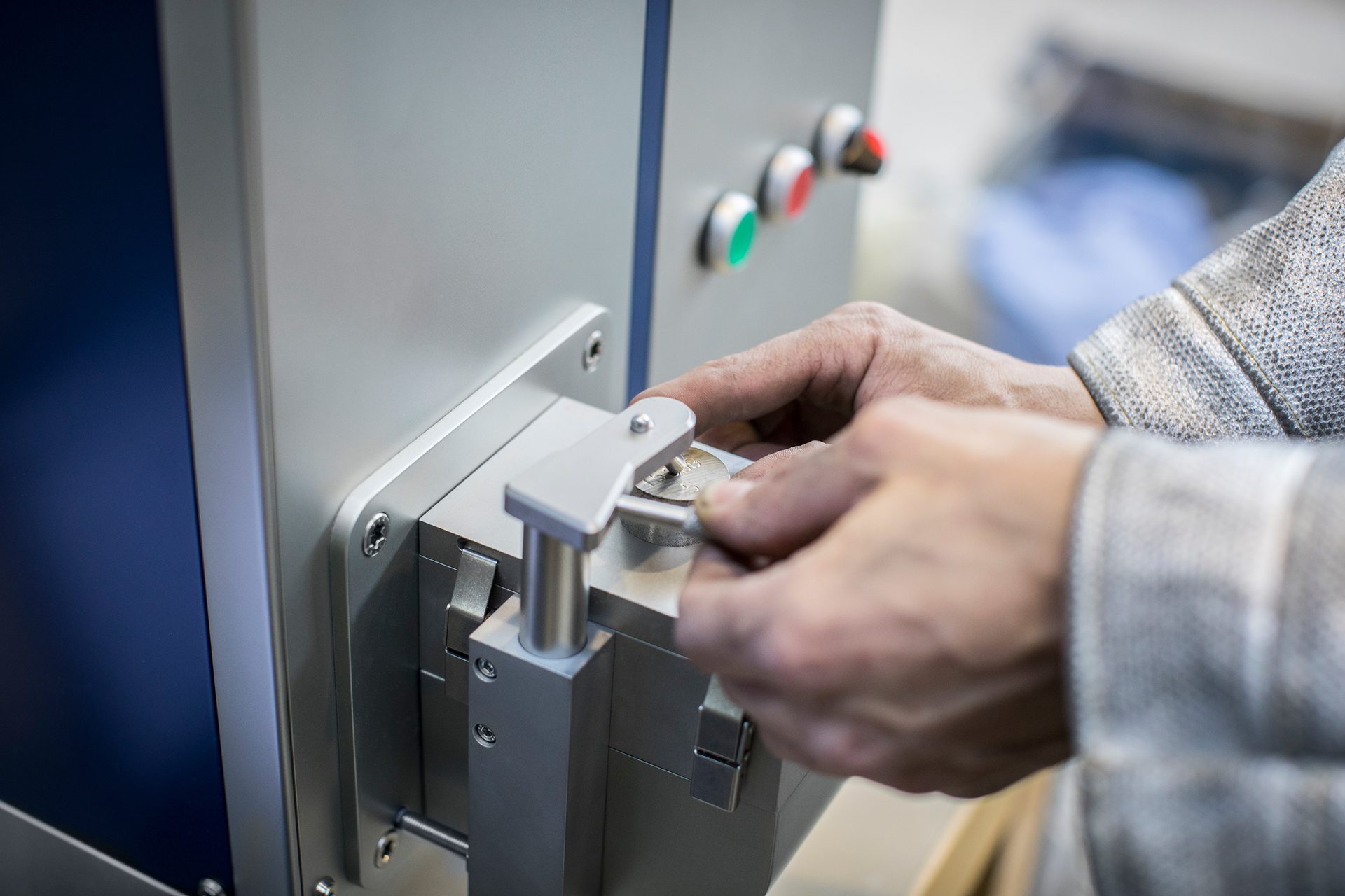 Close-up of hands adjusting a metal disc in a machine for engraving.