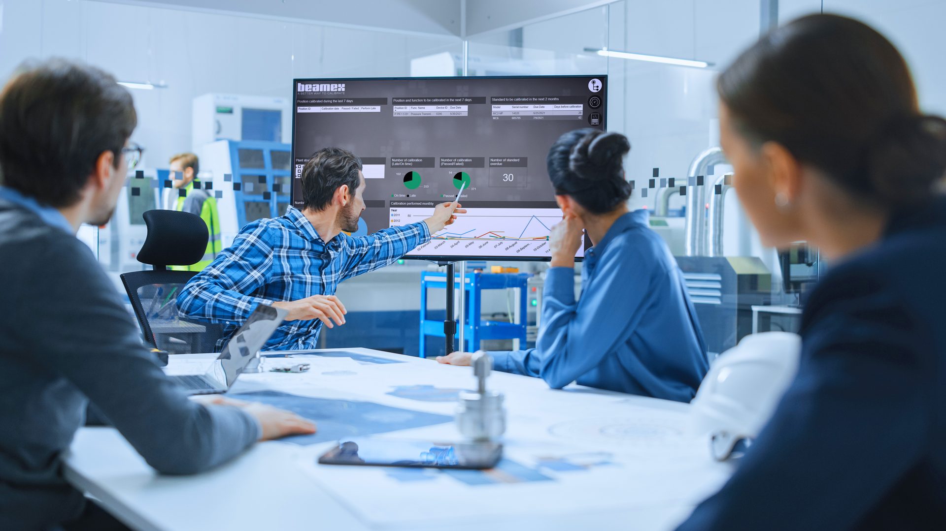 workers sitting at table pointing to monitor