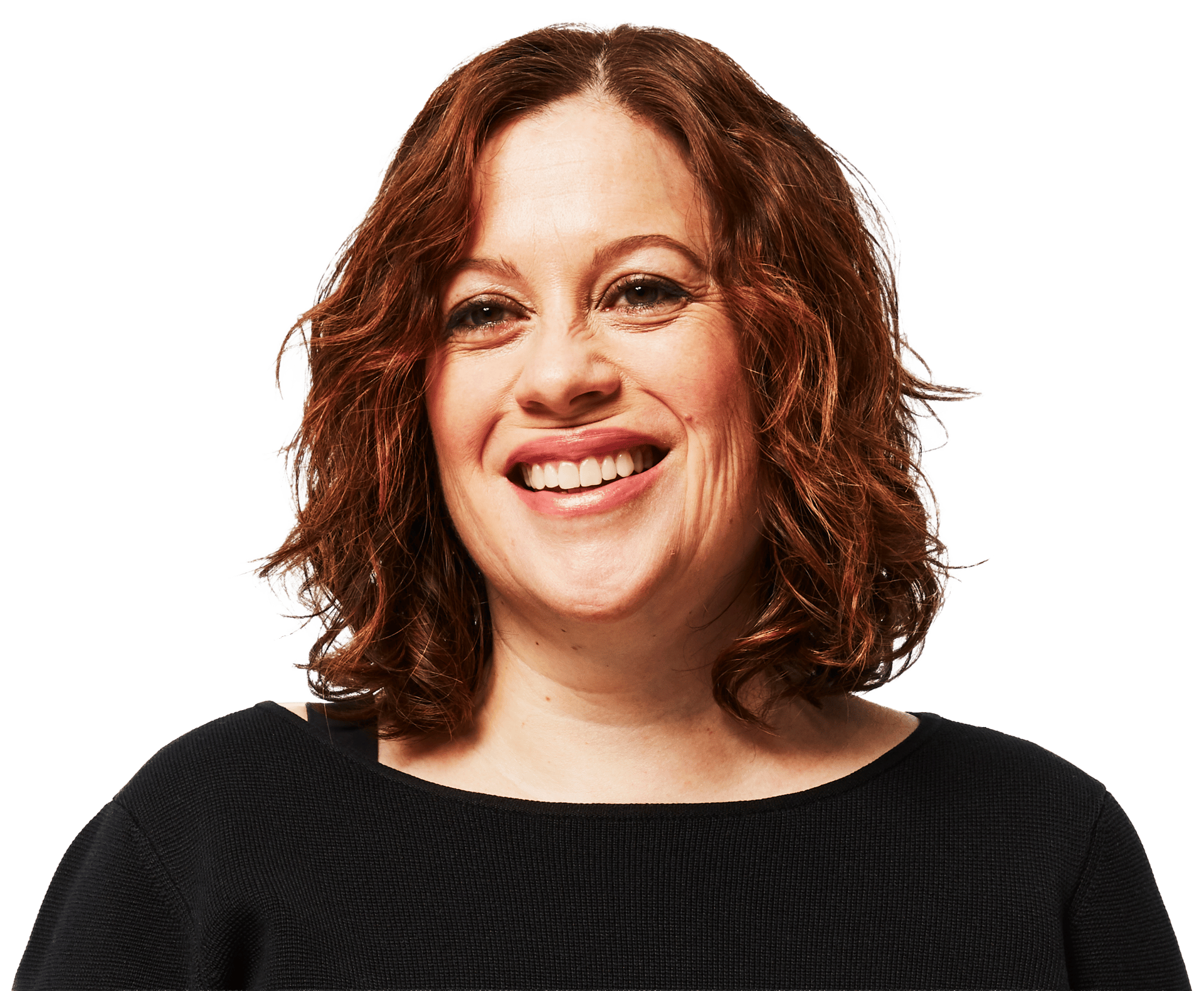 A woman with red-brown, wavy hair smiles widely, wearing a black top against a green background.