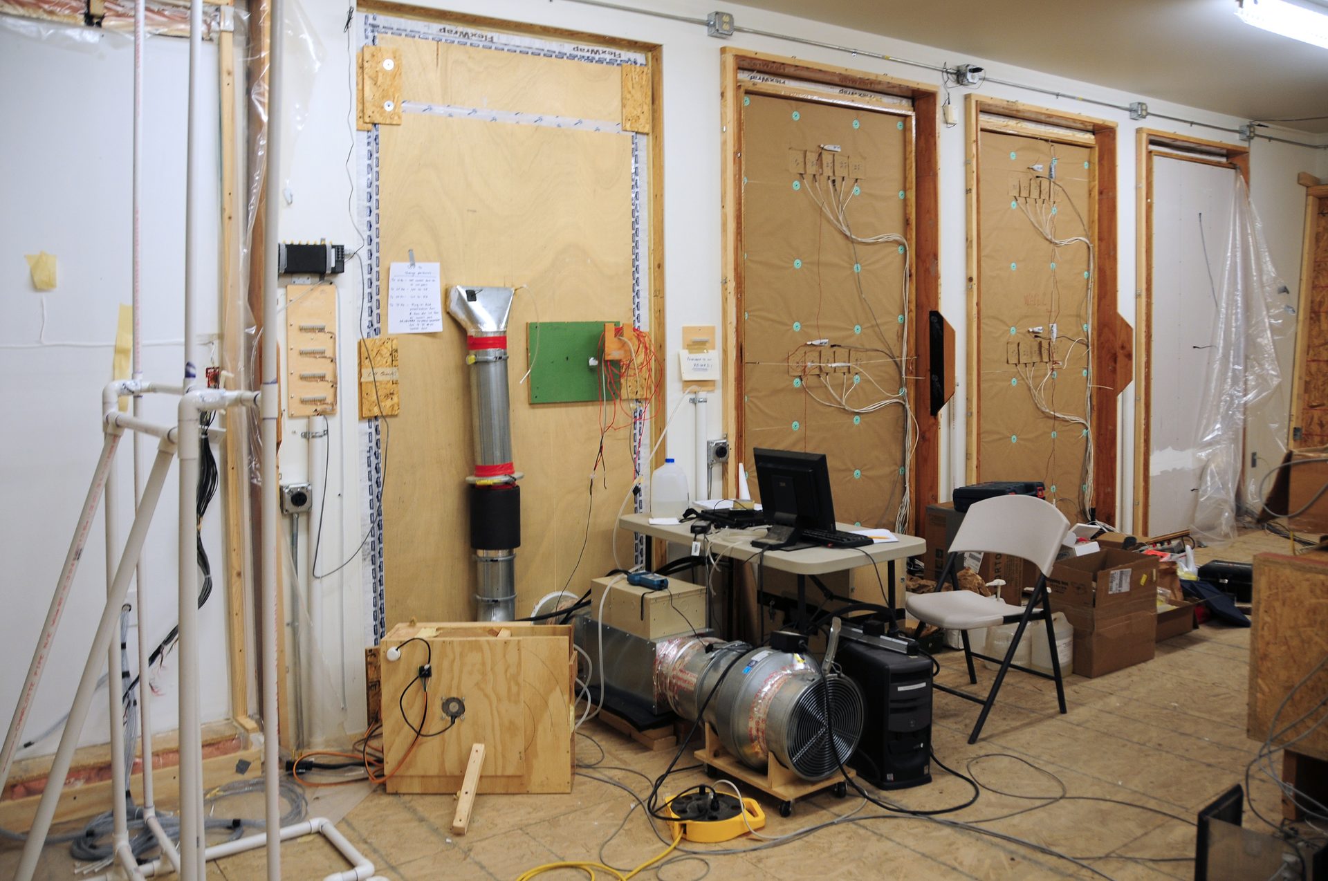 Testing lab setup with walls, pipes, fans, and computer equipment.