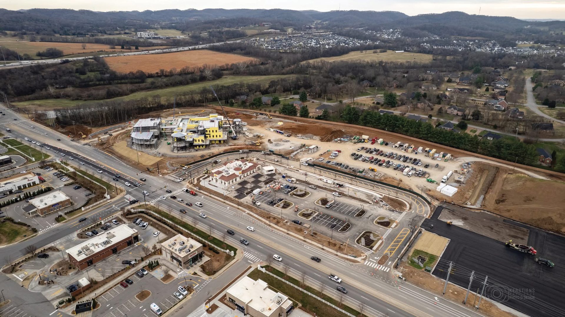 Aerial photo of construction site, buildings, roads, and surrounding residential areas.