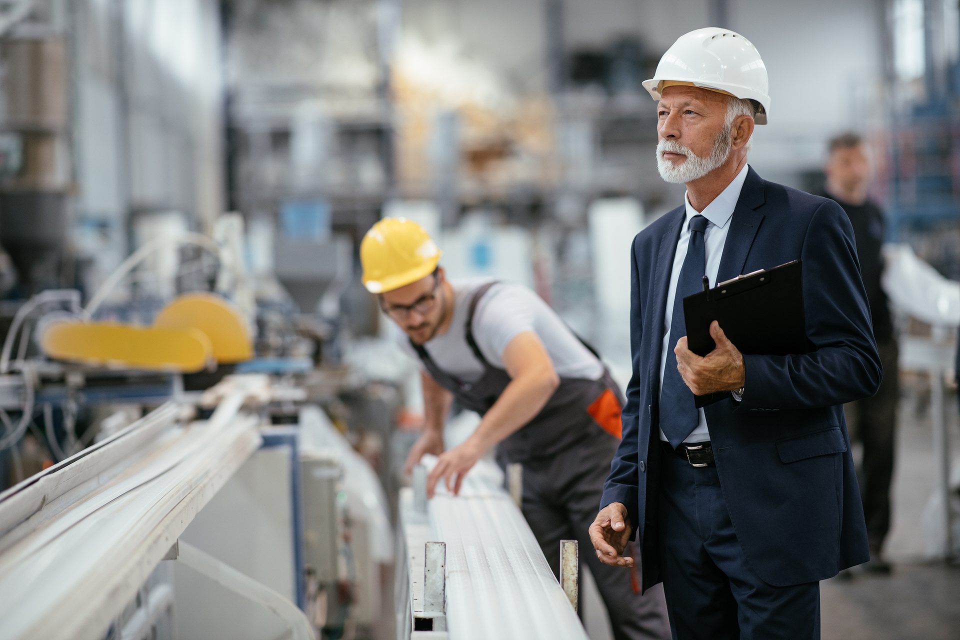 Older manager watching over factory worker