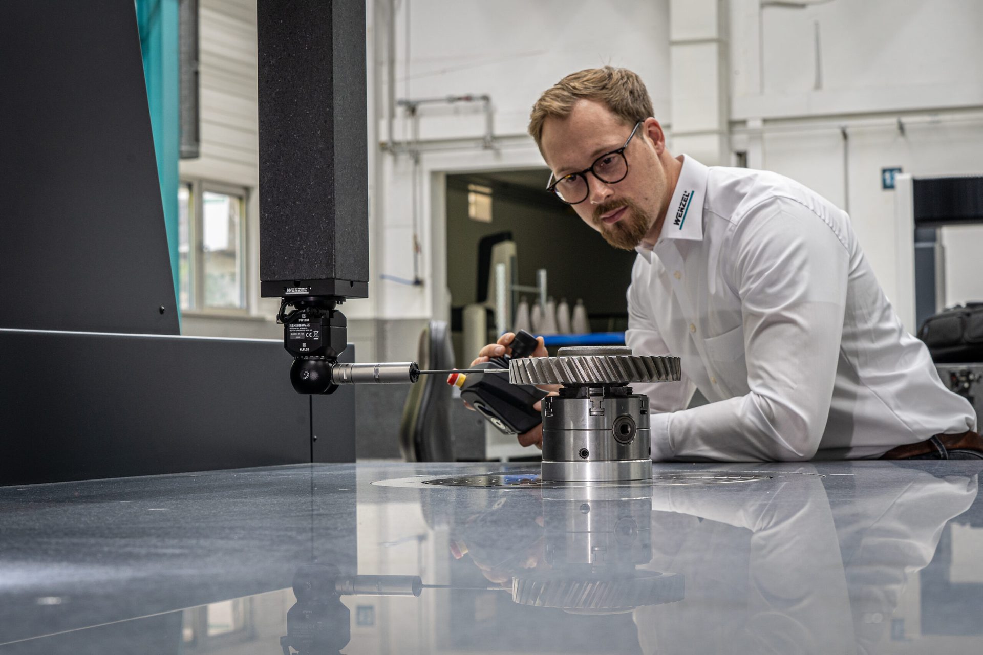 worker using probe stylus to measure geared part