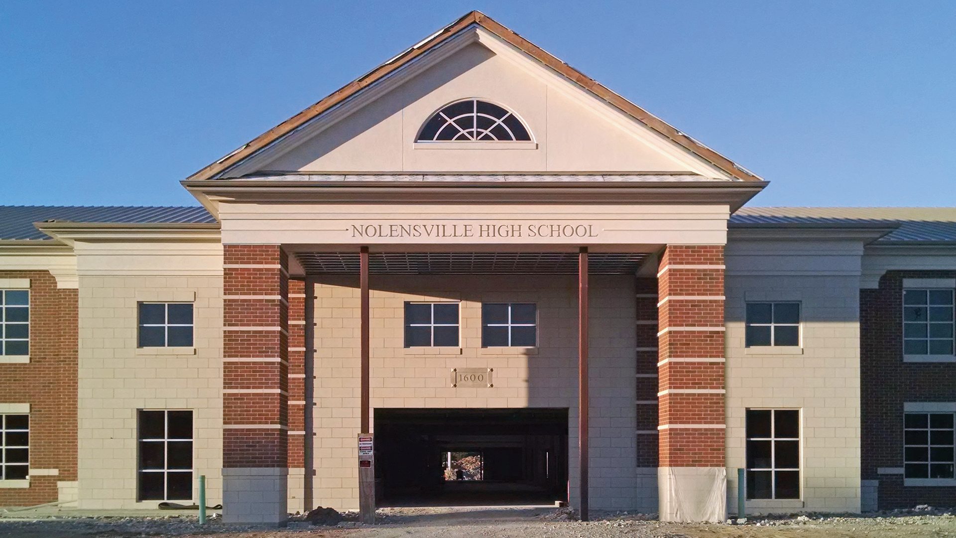 Front facade of Nolensville High School with brick and block, arched window, and prominent entrance.