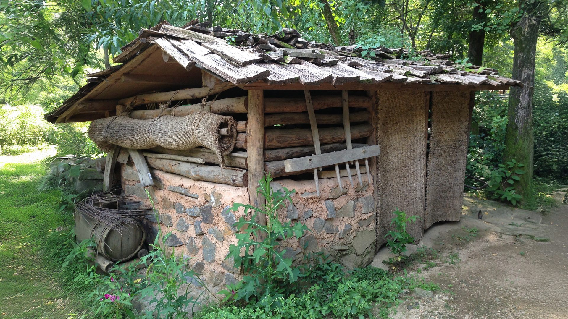 Rustic hut made of logs, stone, and thatch.