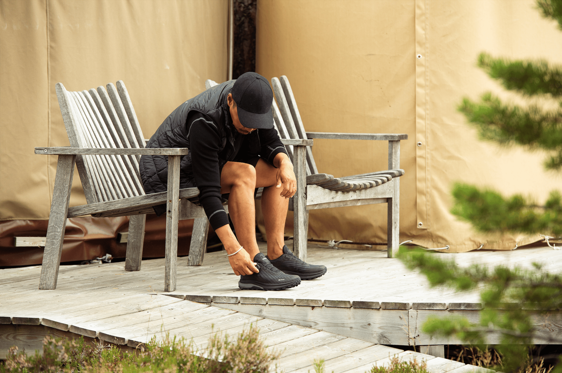 Person adjusts shoe on a wooden deck while sitting on a bench.