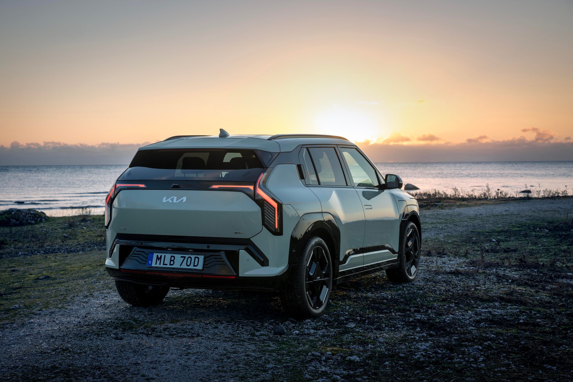Kia EV5 SUV from rear-right by the sea at sunset.