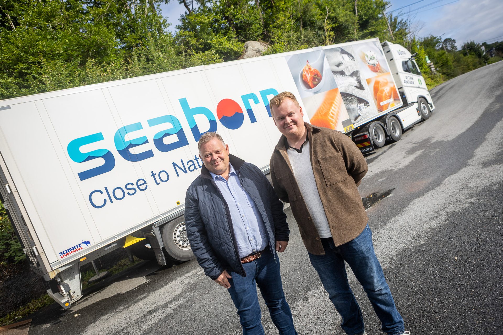 Two smiling men in front of a white Seaborn truck with seafood images and 'Close to Natur' logo.