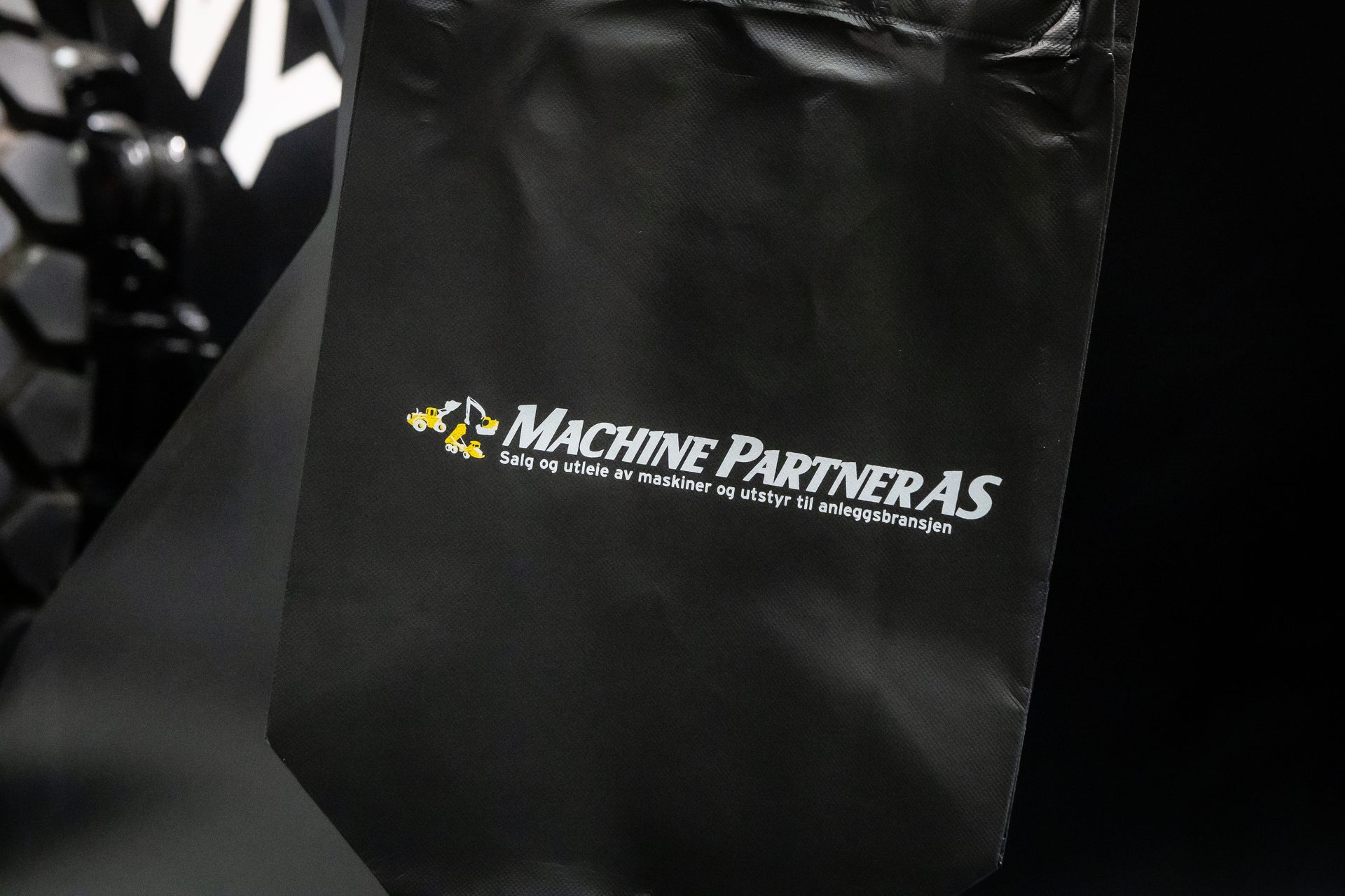 Black bag with Machine Partner AS logo (construction vehicles), slogan: sale & rental.