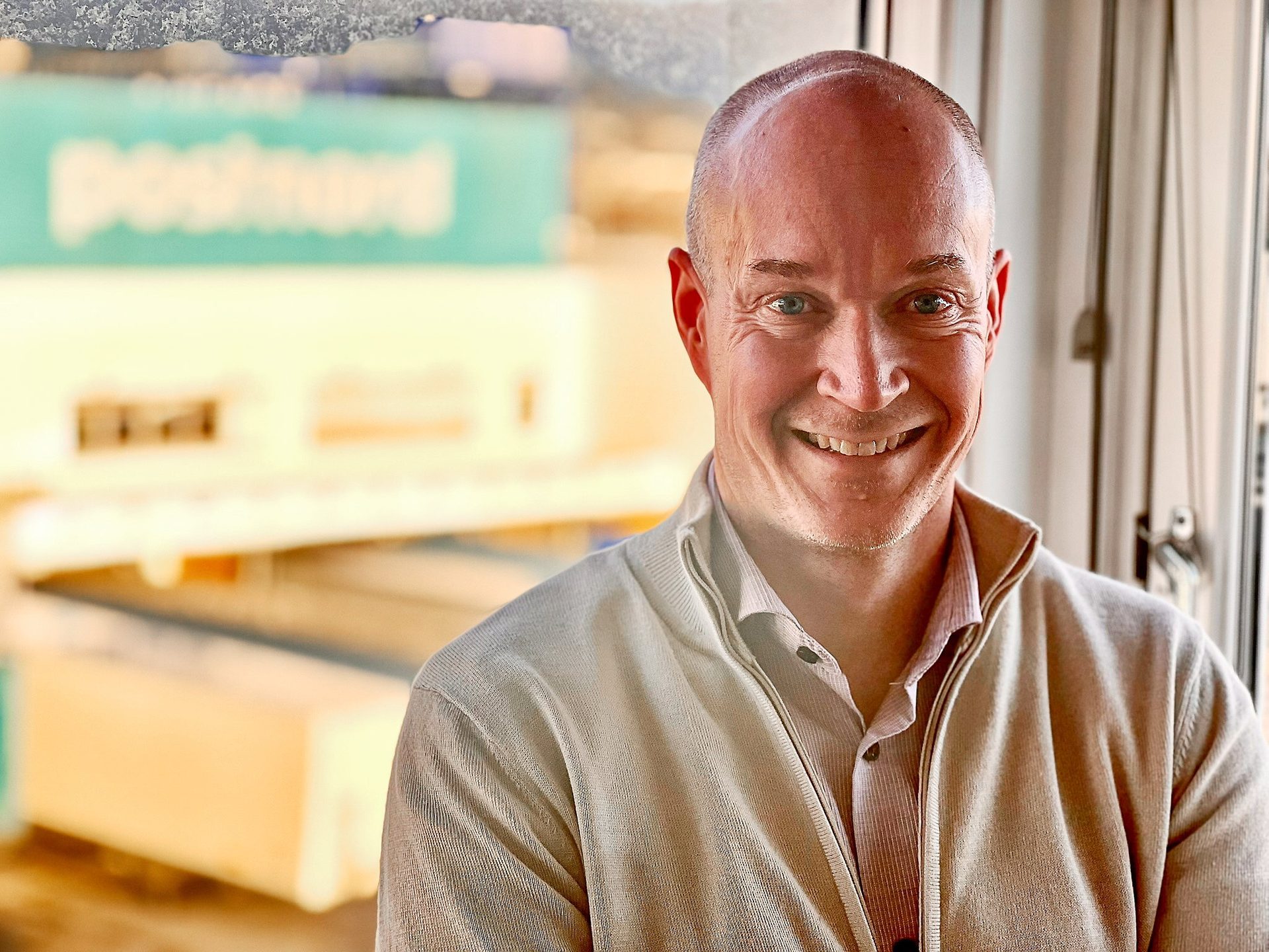A smiling man with a blurred "postnord" background.