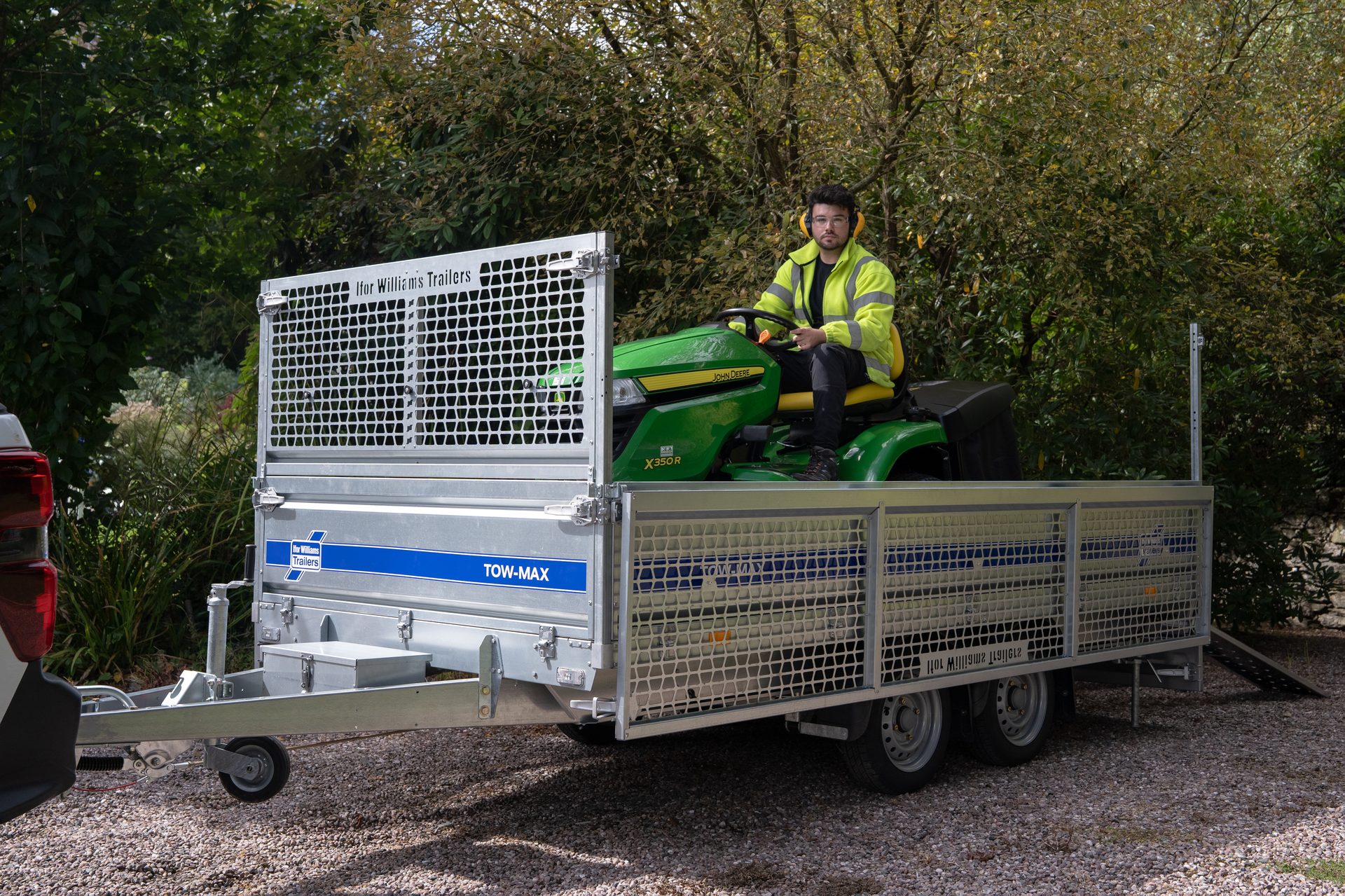Man on John Deere mower loaded on an Ifor Williams TOW-MAX trailer.