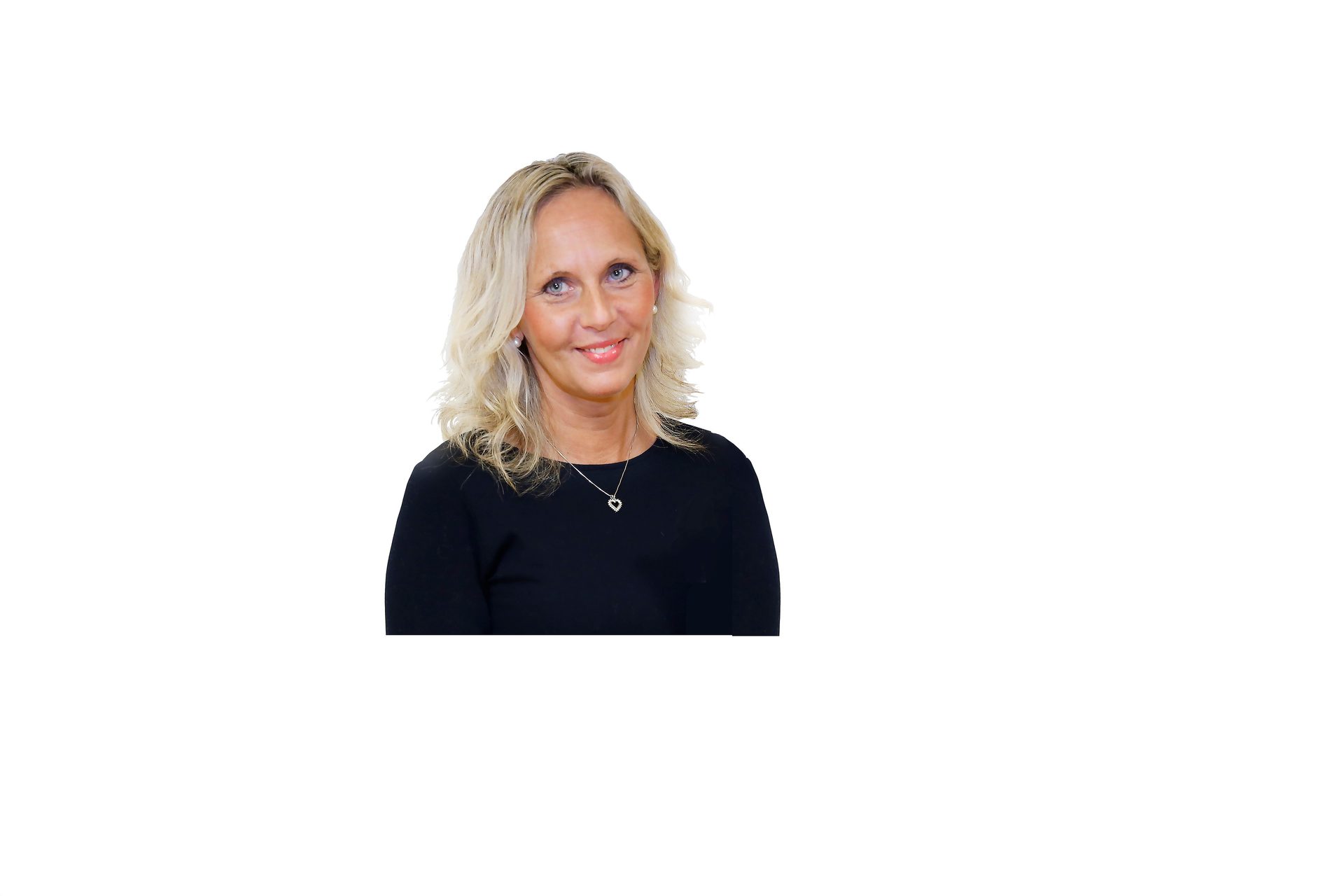 A smiling blonde woman in a black top with a heart necklace against a white background.
