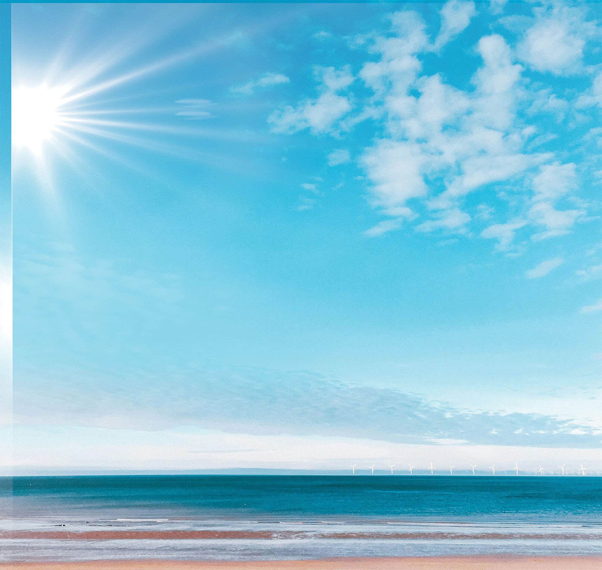 Sun-drenched beach, blue ocean, sky, and distant offshore wind turbines.