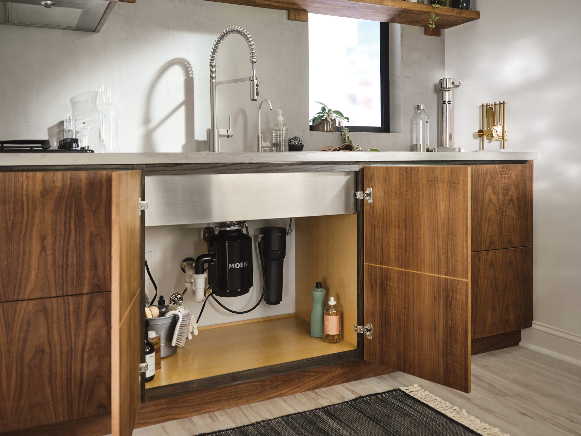 Modern kitchen with open wood cabinets, showing under-sink garbage disposal and water filter.