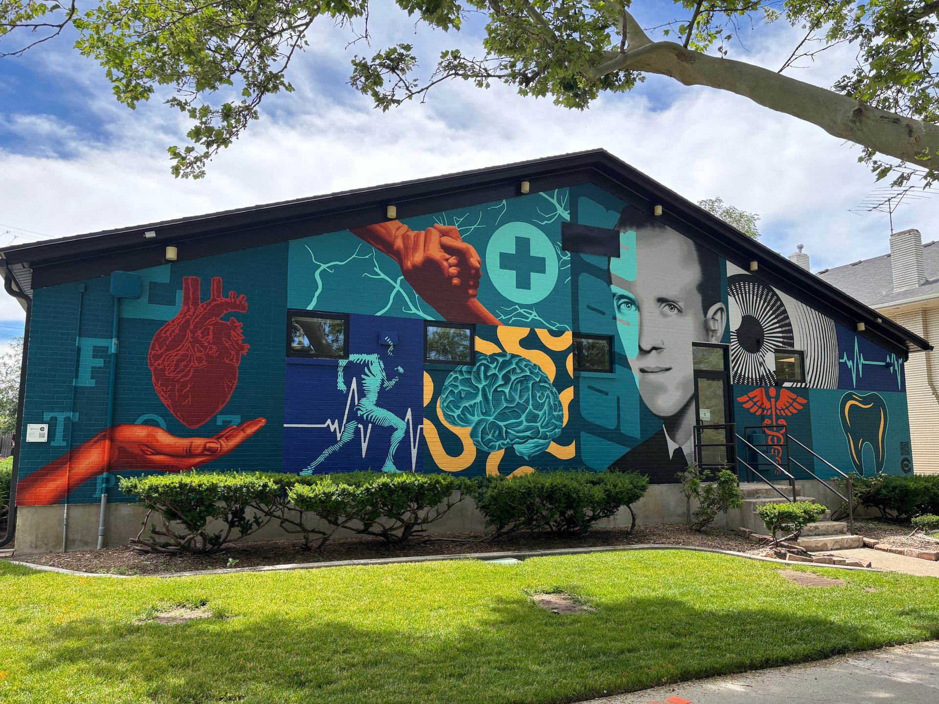 Mural on a building featuring anatomical heart, brain, runner, man's face, and medical symbols.