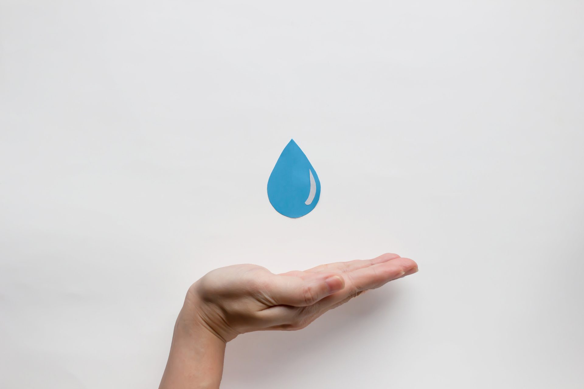 Hand catching a blue paper water drop.