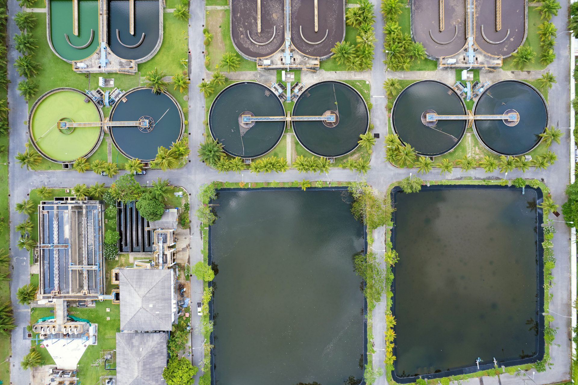 Aerial view of a water treatment plant featuring circular basins and large ponds.