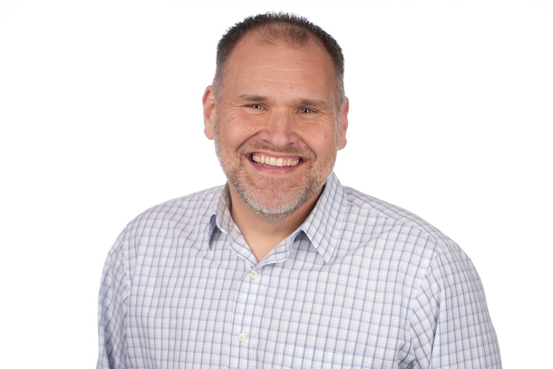 Smiling man with a beard in a plaid shirt on a white background.