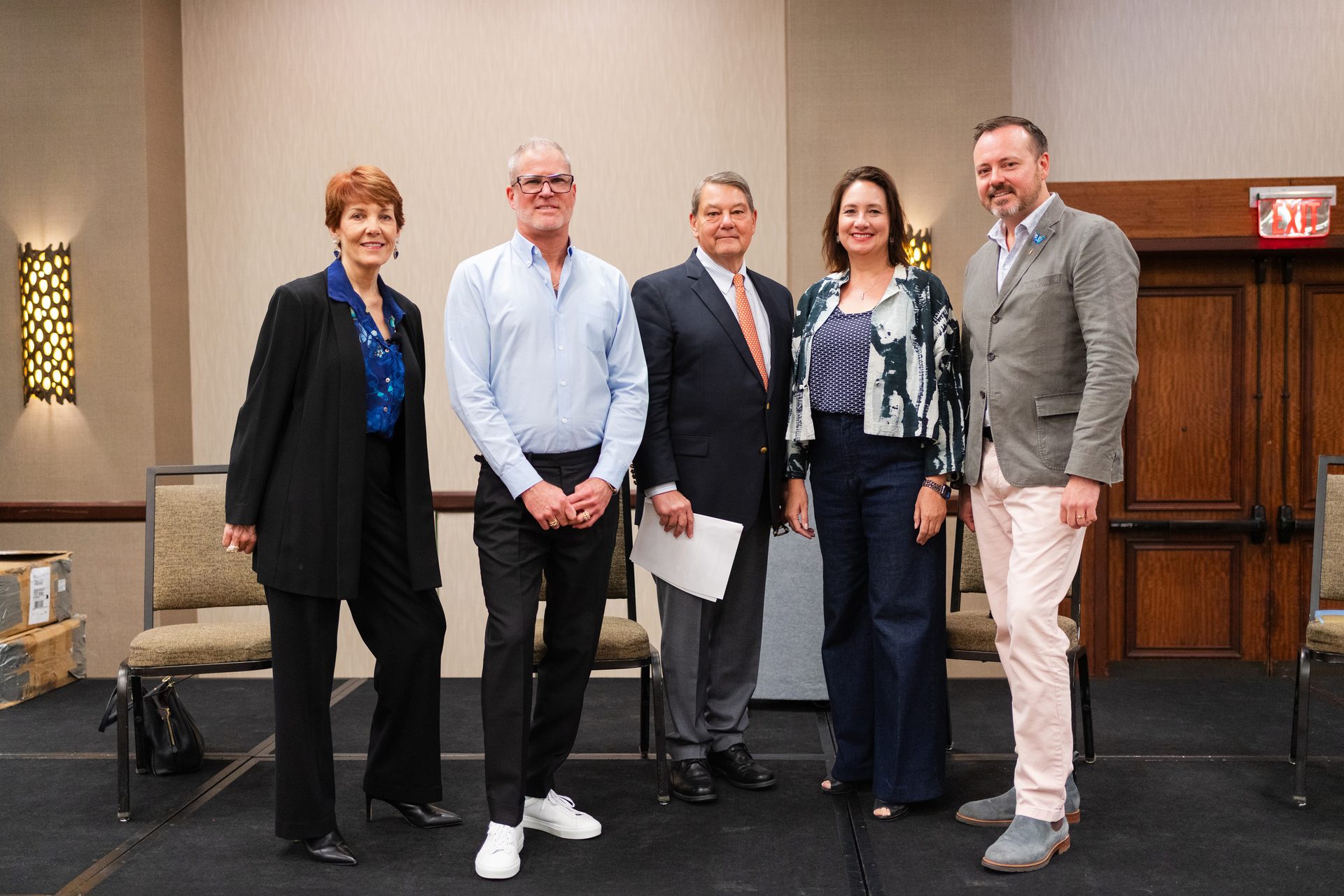Five people pose smiling on a stage.